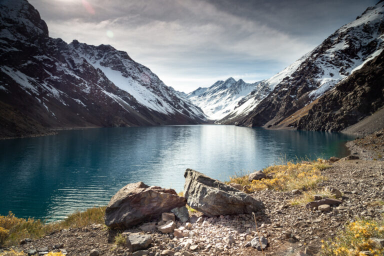 The Laguna del Inca lake surrounded by high mountains covered in snow in Chile