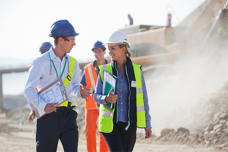 A group of construction workers talking in front of a construction site.