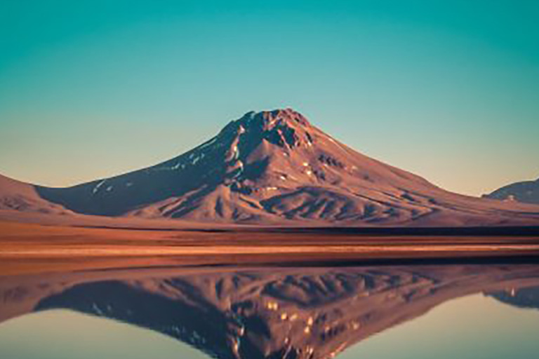 A mountain is reflected in a body of water.